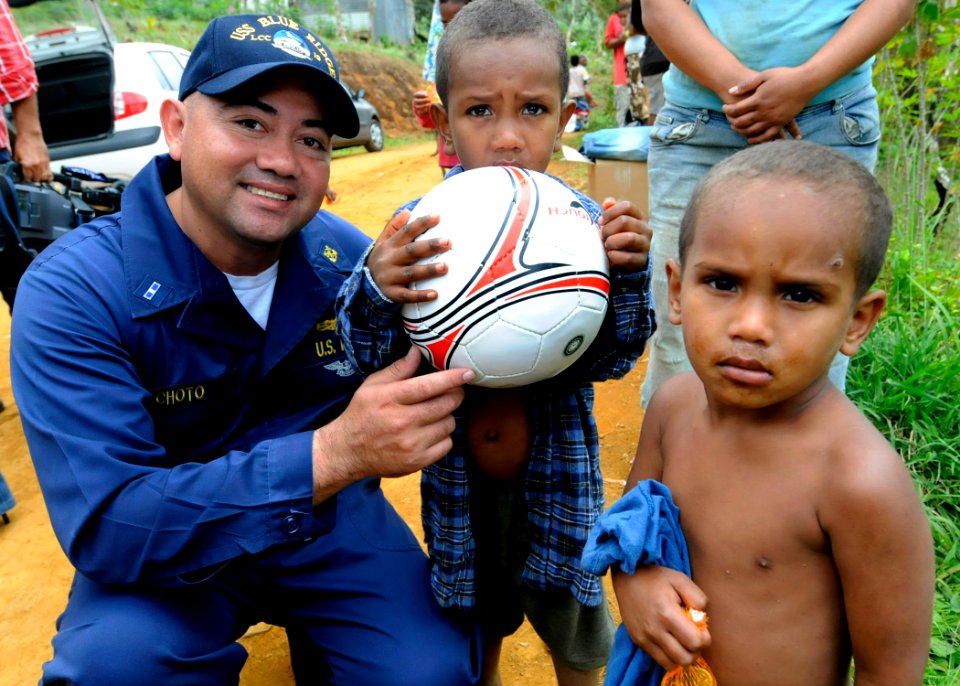US Navy 090925-N-7478G-357 Chief Warrant Officer 3 Carlos Choto, assigned to the amphibious command ship USS Blue Ridge (LCC 19), poses with children after giving them a soccer ball during a community relations project