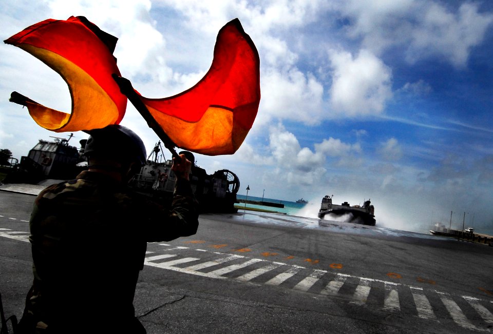 US Navy 090930-N-0807W-028 Boatswain Mate 3rd Class Edgar S. Nicholson, ramp marshal for Assault Craft Unit (ACU) 5, signals a landing craft, air cushion (LCAC) as it comes ashore during LCAC operations photo