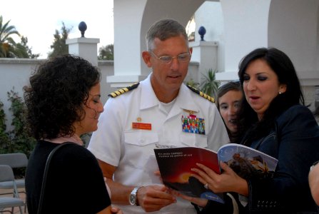 US Navy 090929-N-3289C-017 Laura Buada Fenix, the 2008 Queen of the Damas, looks on while Capt. Bill Mosk, commanding officer of Naval Station Rota, is shown pages from the 2008
