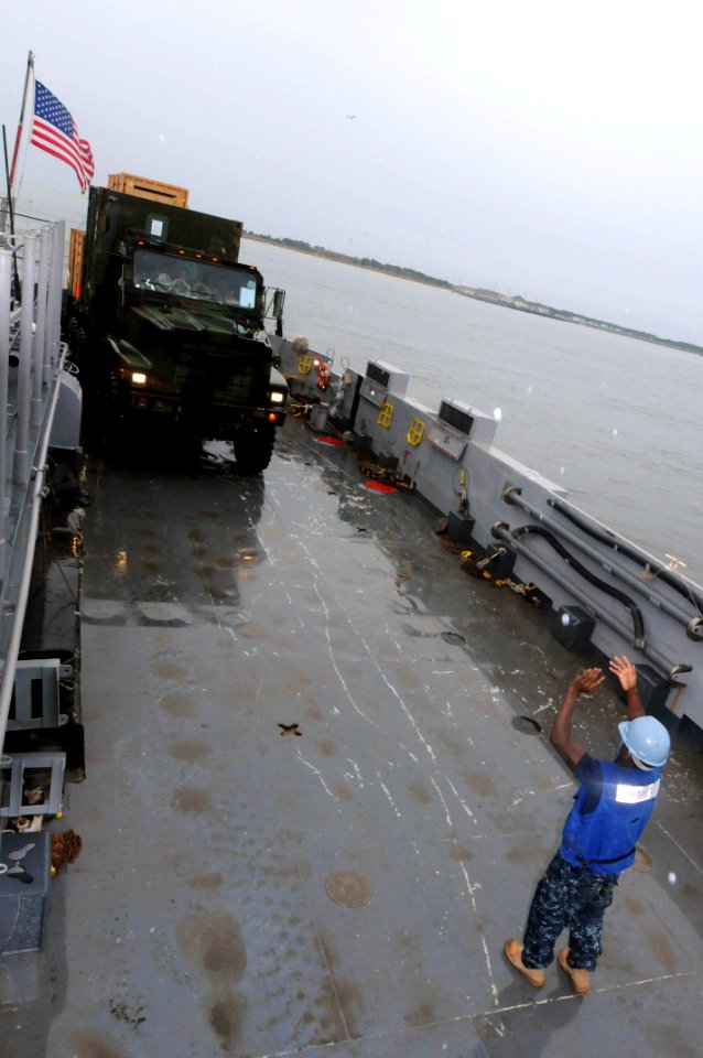 US Navy 091005-N-0890S-085 Boatswain's Mate 3rd Class James Daywea, assigned to Assault Craft Unit (ACU) 2, loads a Marine truck onto Landing Craft Unit (LCU) 1653