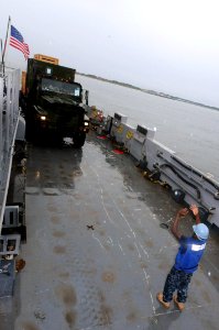 US Navy 091005-N-0890S-085 Boatswain's Mate 3rd Class James Daywea, assigned to Assault Craft Unit (ACU) 2, loads a Marine truck onto Landing Craft Unit (LCU) 1653