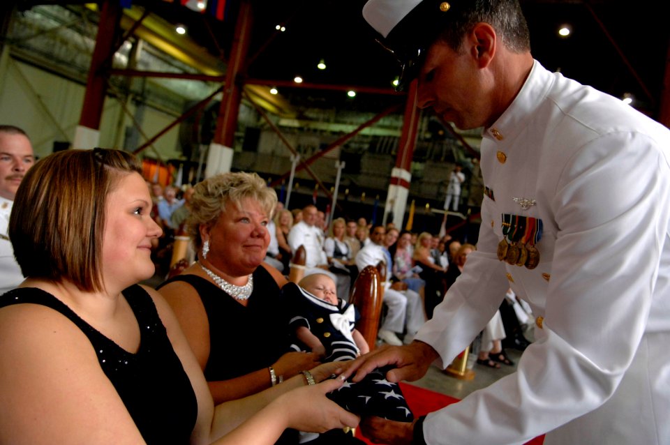 US Navy 091002-N-9818V-641 An American flag is presented to Mrs. Tiffany Dixon and daughter after Old Glory is read at the retirement ceremony for her father