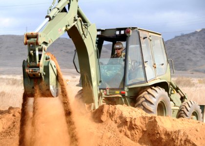 US Navy 091007-N-1424C-171 A Seabee assigned to amphibious construction battalion ONE (ACB-1) controls a backhoe loader to construct part of the life support area (LSA) for 800 military personnel