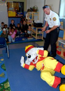 US Navy 091005-N-9860Y-003 Cliff Foley, a Navy Region Northwest Fire and Emergency Services fire inspector, and Sparky the Fire Dog demonstrate stop, drop and roll to School Age Care Programs students