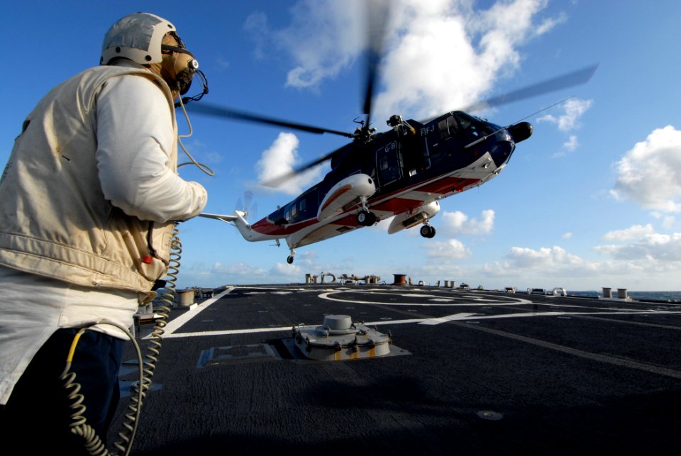 US Navy 091006-N-1688B-184 Interior Communications Electrician 1st Class Ryan Ratts, the flight deck safety officer aboard the guided missile destroyer USS Cole (DDG 67), observes a British civilian helicopter land during fligh