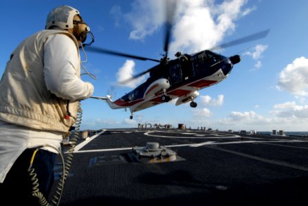 US Navy 091006-N-1688B-184 Interior Communications Electrician 1st Class Ryan Ratts, the flight deck safety officer aboard the guided missile destroyer USS Cole (DDG 67), observes a British civilian helicopter land during fligh