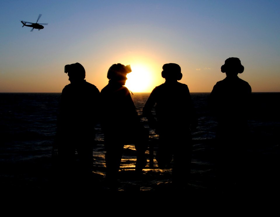 US Navy 091007-N-7478G-360 Sailors assigned to the flight deck crew of the amphibious command ship USS Blue Ridge (LCC 19) watch the sunset and the arrival of an SH-60F Sea Hawk helicopter