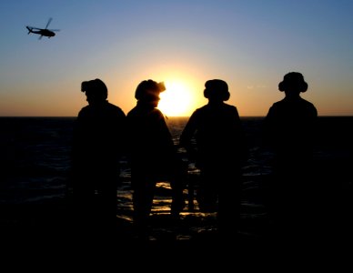 US Navy 091007-N-7478G-360 Sailors assigned to the flight deck crew of the amphibious command ship USS Blue Ridge (LCC 19) watch the sunset and the arrival of an SH-60F Sea Hawk helicopter
