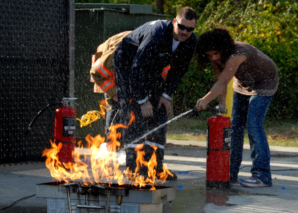 US Navy 091005-N-9860Y-001 Alan Sprouse, a Navy Region Northwest Fire and Emergency Services fire inspector, helps a School Age Care Programs student extinguish a grease fire