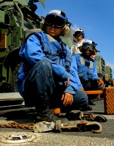US Navy 091008-N-5345W-017 Seaman John Mendez, left, Boatswain's Mate Seaman Antoinette Smith and Boatswain's Mate 1st Class Jay Collette watch an approaching helicopter from the flight deck of the amphibious dock landing ship