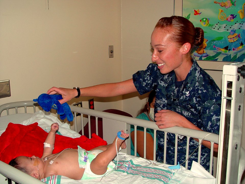 US Navy 091005-N-2888Q-003 Hospital Corpsman 2nd Class Amanda Valenzuela, assigned to Navy Operational Support Center Albuquerque, gives an infant a Navy bear as part of a Caps For Kids visit to the pediatric department of Pres
