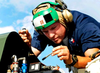 US Navy 091007-N-7478G-362 Aviation Structural Mechanic 1st Class Lawrence Smathers, assigned to Light Helicopter Antisubmarine Squadron (HSL) 51, performs preventive maintenance under the top hood of an SH-60F Sea Hawk helicop