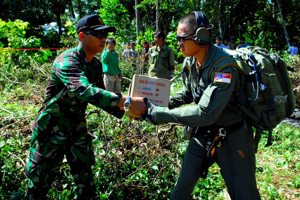 US Navy 091009-N-9123L-108 Indonesian Air Force 1st Lt. Prasetyo Aguswouo and Air Force Capt. Tony Truong, from Los Angeles, Calif., unload relief supplies from a CH-53E Super Stallion helicopter assigned to the Dragons of Mari