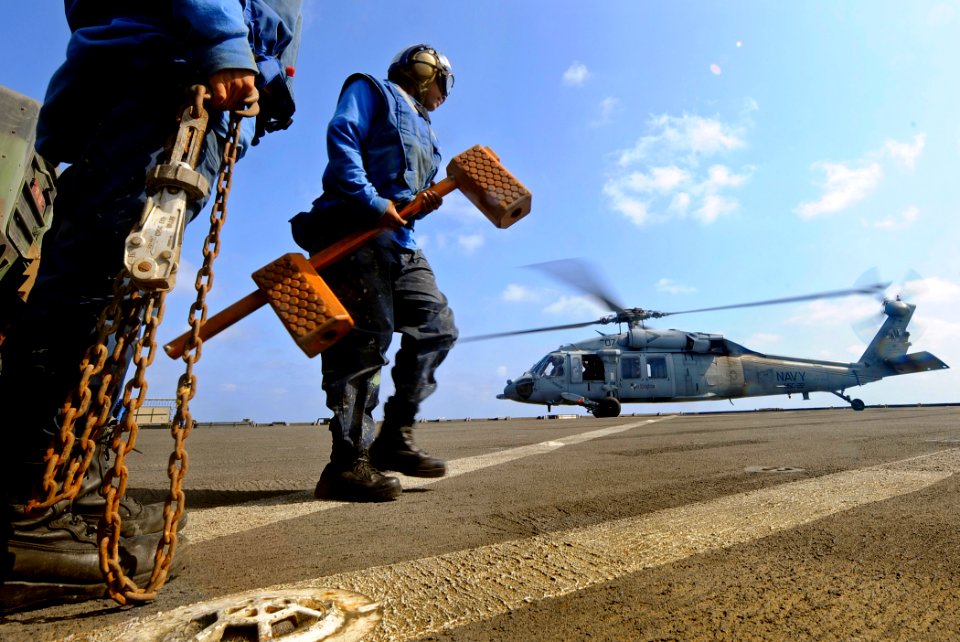 US Navy 091008-N-5345W-028 Boatswain's Mate Seaman Antoinette Smith stands by to place chocks on an MH-60S Sea Hawk helicopter from Helicopter Sea Combat Squadron (HSC) 22 as it lands on the flight deck of the amphibious dock l