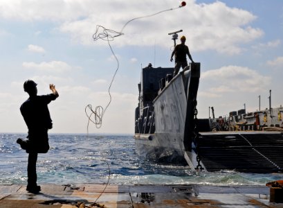US Navy 091010-N-1831S-114 Boatswain's Mate Seaman Sean Church casts a heaving line to a landing craft utility from Assault Craft Unit (ACU) 2 as it docks with the amphibious dock landing ship USS Fort McHenry (LSD 43)