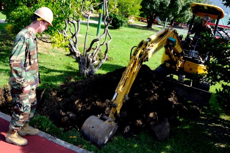 US Navy 091008-N-8335D-167 Construction Electrician 2nd Class Eric Smith of Rochester, N.Y., directs Equipment Operator 2nd Class Brandon Martin, as he digs a hole for a construction project at Fleet Activities, Sasebo