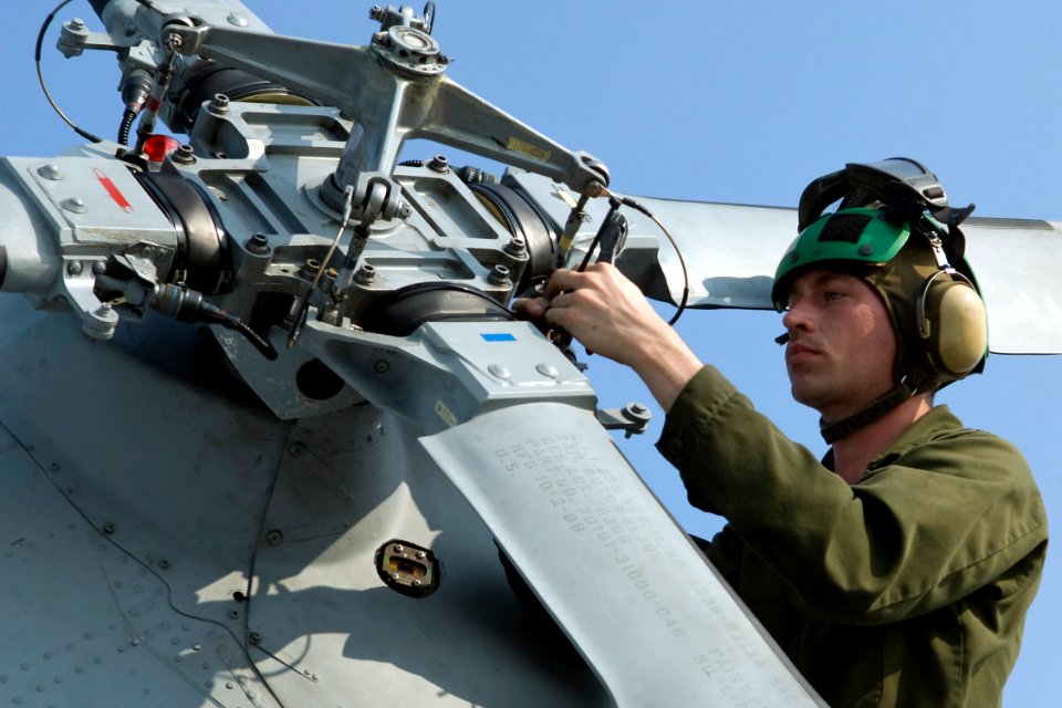 US Navy 091008-N-9123L-009 Aviation Machinist Mate Airman Bryan Cooper, assigned to the Warlords of Helicopter Anti-submarine Squadron Light (HSL) 51, tightens the tail rotor blades of an SH-60B Sea Hawk