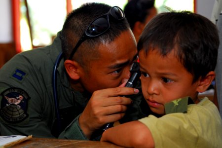 US Navy 091009-N-9123L-147 Air Force Capt. Tony Truong, a Los Angeles, Calif. native assigned to the 353 special operations squadron, checks a child ears