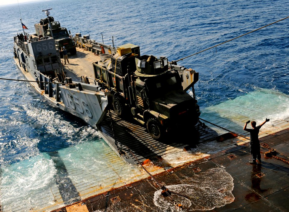 US Navy 091010-N-5345W-155 A deck department Sailor assigned to the amphibious dock landing ship USS Fort McHenry (LSD 43) guides the driver of a Marine medium tactical vehicle replacement (MTVR)