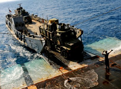 US Navy 091010-N-5345W-155 A deck department Sailor assigned to the amphibious dock landing ship USS Fort McHenry (LSD 43) guides the driver of a Marine medium tactical vehicle replacement (MTVR)