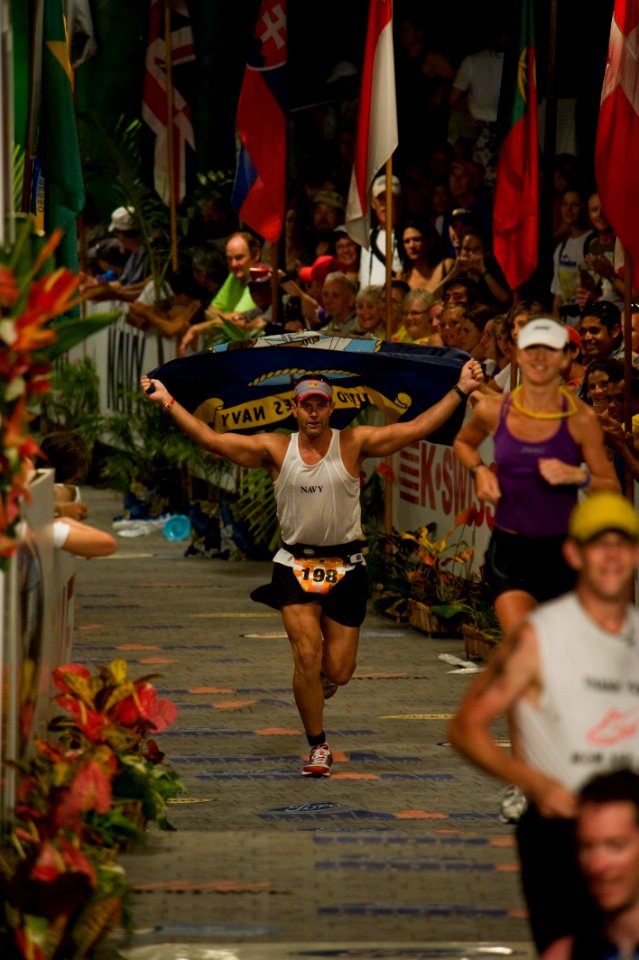 US Navy 091010-N-0555B-037 Lt. Cmdr. Don Cross, a submarine officer from Merritt Island, Fla., carries the Navy flag across the finish line of the 2009 Ford Ironman World Championship in Kailua-Kona, Hawaii