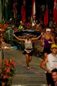 US Navy 091010-N-0555B-037 Lt. Cmdr. Don Cross, a submarine officer from Merritt Island, Fla., carries the Navy flag across the finish line of the 2009 Ford Ironman World Championship in Kailua-Kona, Hawaii