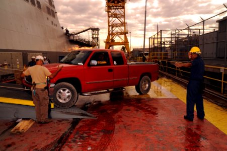 US Navy 091010-N-2147L-001 Boatswain's Mate 3rd Class Franklin Rendo directs vehicles aboard the amphibious transport dock ship Pre-Commissioning Unit (PCU) New York (LPD 21) photo