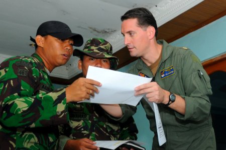 US Navy 091011-N-9950J-088 Lt. Cmdr. Ian Johnston, air operations planner during the Indonesian humanitarian assistance operation, reviews a flight plan with Indonesian army officers at Tabing Airfield photo