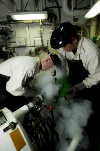 US Navy 091012-N-3038W-227 Aircrew Survival Equipmentman 2nd Class Andrew Wardell, left, and Survival Equipmentman 3rd Class Khamphone Nhoybovakong release liquid oxygen while performing maintenance aboard the aircraft carrier
