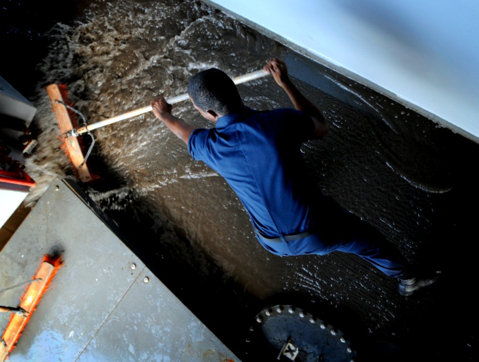 US Navy 091012-N-3830J-218 Seaman Romel Thomas sweeps water off the port sponson aboard the amphibious command ship USS Blue Ridge (LCC 19)