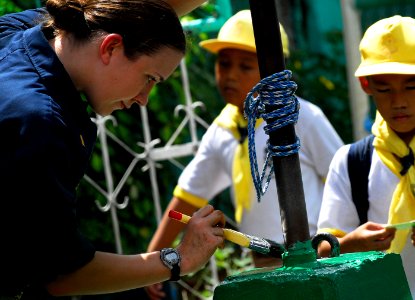 US Navy 091015-N-0807W-307 Ensign Whitney Steiger, assigned to the amphibious dock landing ship USS Harpers Ferry (LSD 49), paints the base of a flagpole during a community service project at West Central Elementary School