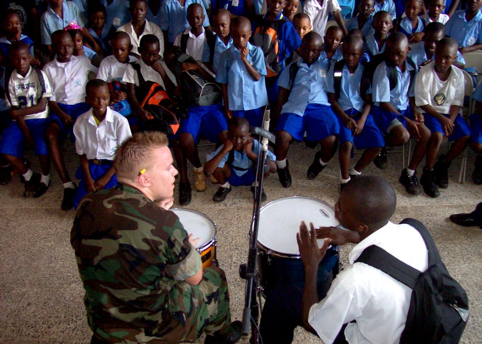 US Navy 091015-N-8332M-002 Musician 3rd Class Jason McDonough, a member of the Commander, U.S. Naval Forces Europe rock band, Flagship, performs with a local student at the SOS International School