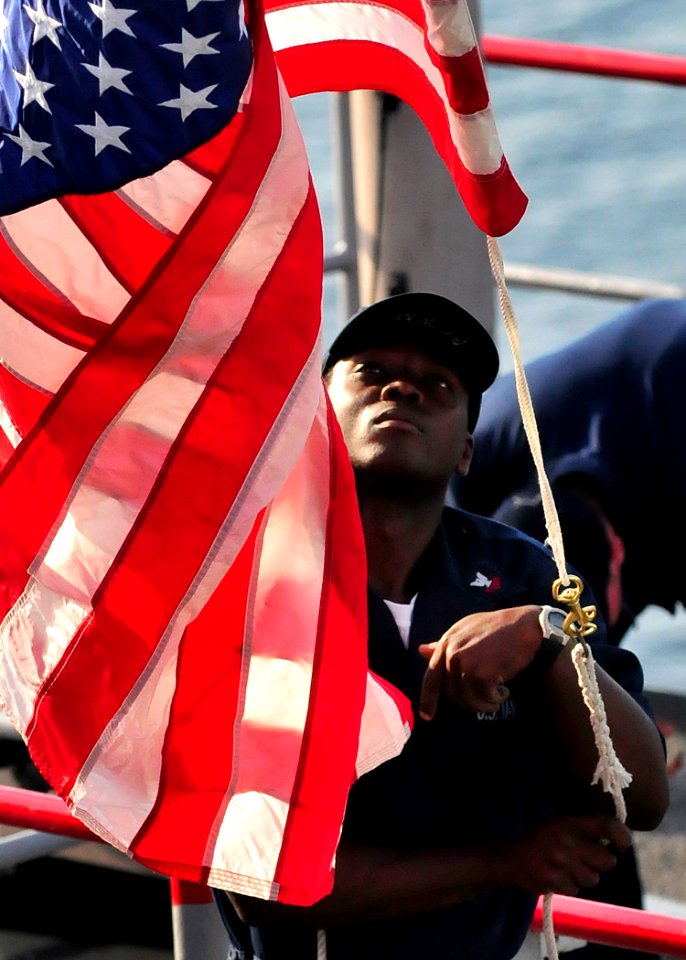 US Navy 091020-N-0807W-032 Quartermaster 2nd Class Matthew M. Brook raises the American flag as the amphibious dock landing ship USS Harpers Ferry (LSD 49) gets underway