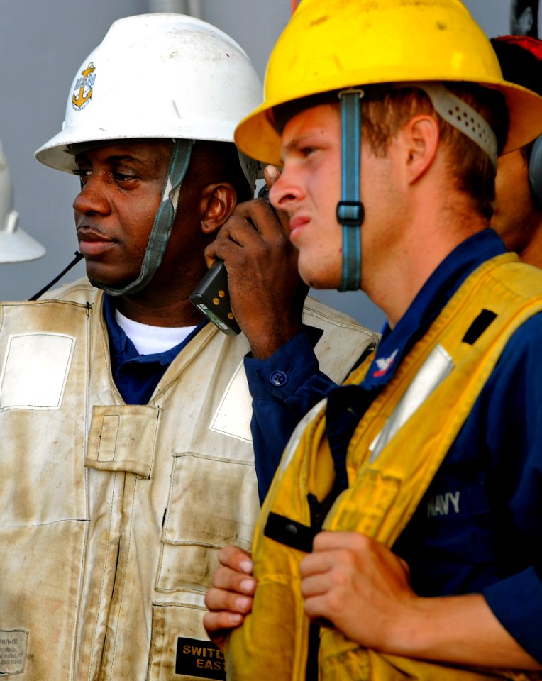 US Navy 091016-N-5345W-077 Chief Boatswain's Mate Jiamon Poe, left, and Boatswain's Mate 2nd Class Austen Gant watch from the portside replenishment station as the amphibious dock landing ship USS Fort McHenry (LSD 43) brings o