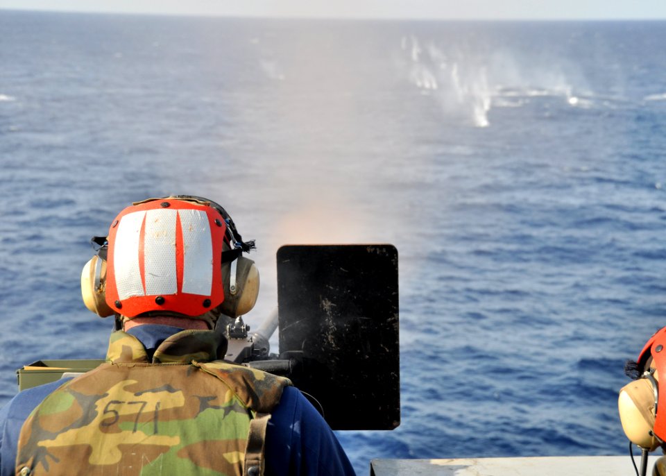 US Navy 091020-N-2013O-040 Aviation Boatswain's Mate (Fuel) 3rd Class Robert Haworth, assigned to the air department aboard the aircraft carrier USS George Washington (CVN 73) fires a .50-caliber machine gun