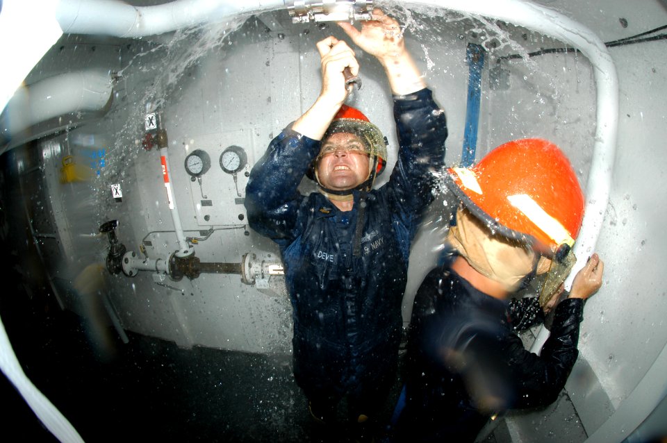 US Navy 091020-N-7498L-014 Hull Maintenance Technician 1st Class David Devoe, left, patches a pipe during damage control training at the Center of Naval Engineering Learning Site Pearl Harbor