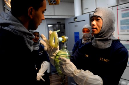 US Navy 091021-N-3830J-055 Cmdr. Tri Lac, medical officer demonstrates the proper use of an air mask to hospital corpsmen and stretcher bearers in the main battle dressing station during a general quarters drill