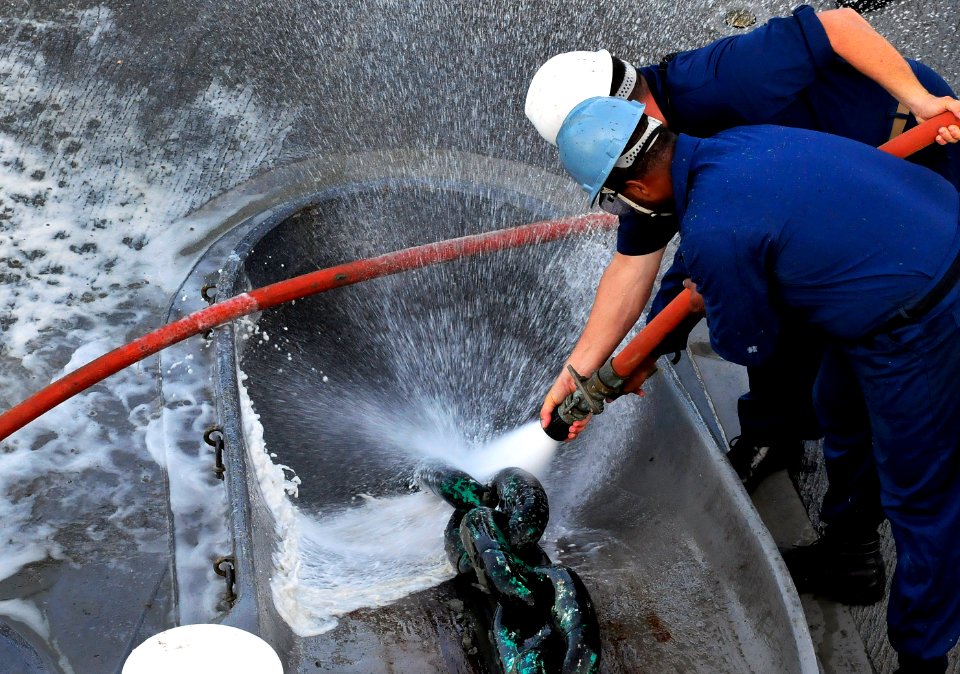 US Navy 091020-N-0807W-109 Chief Boatswain's Mate Eric M. Randall and Seaman Jerald M. Brooks aboard the amphibious dock landing ship USS Harpers Ferry (LSD 49) wash debris from the anchor chain