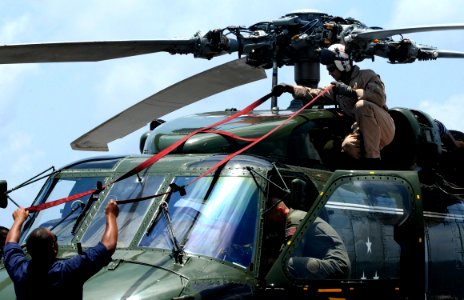 US Navy 091022-N-7478G-278 Lt. Cmdr. Loren Romeus, assigned to Helicopter Antisubmarine Squadron Light (HSL) 51, attaches straps to the top hood of an SH-60F Sea Hawk helicopter for inspection before flight quarters