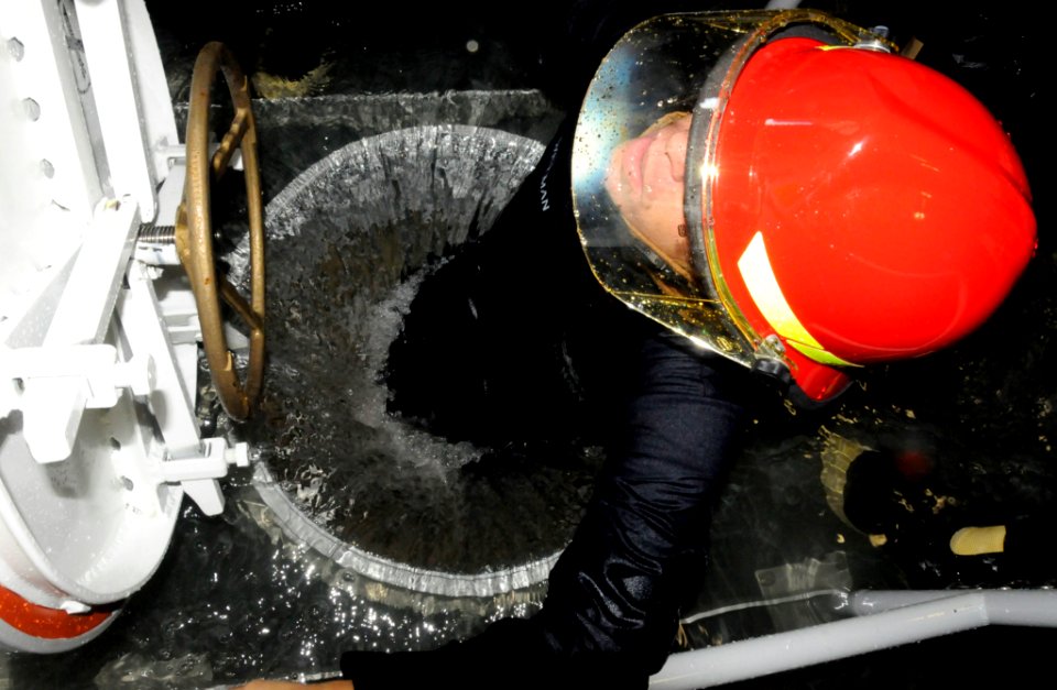 US Navy 091020-N-7498L-103 Damage Controlman 2nd Class Ken Wiseman climbs up a flooded hatch during damage control training at the Center of Naval Engineering Learning Site Pearl Harbor