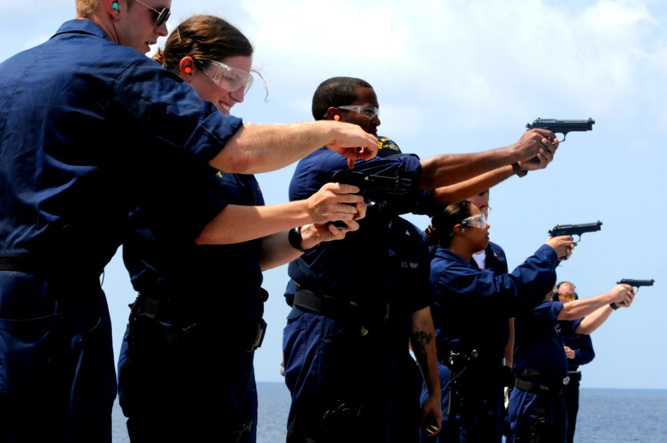 US Navy 091021-N-7478G-254 Ensign Jaime Howe receives guidance on her 9mm pistol during a small-arms weapon qualification aboard the amphibious command ship USS Blue Ridge (LCC 19)