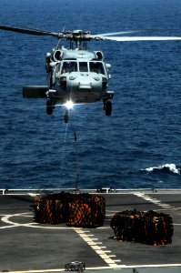 US Navy 091022-N-3038W-613 An MH-60S Sea Hawk helicopter drops unused or unusable parts on the flight deck of the Military Sealift Command fast combat support ship USNS Bridge (T-AOE 10) during a replenishment at sea with the a