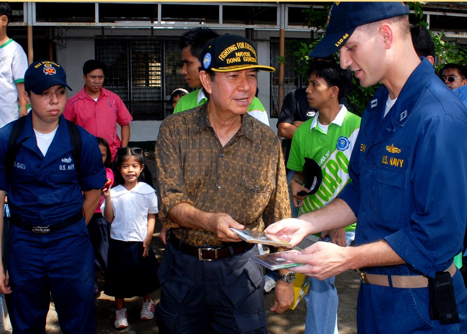 US Navy 091026-N-6692A-060 Olongapo City Mayor James Gordon presents compact discs to Lt. Adam Stein, the operations officer aboard the dock landing ship USS Tortuga (LSD 46)