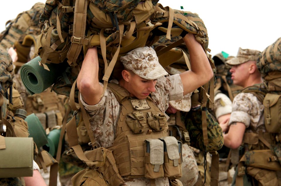 US Navy 091027-N-3592S-044 Lance Cpl. Brandon Focer, an A-gunner with Charlie Company, 2nd Platoon, 24th Marine Expeditionary Unit, heaves his pack over his head as he and other Marines wait to board landing craft utilities