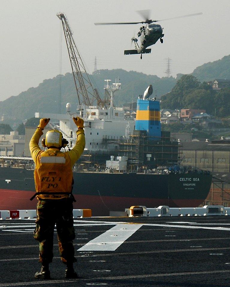 US Navy 091027-N-5215E-055 Aviation Boatswain's Mate 2nd Class Eric Ballard guides an MH-60s Sea Hawk helicopter
