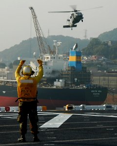 US Navy 091027-N-5215E-055 Aviation Boatswain's Mate 2nd Class Eric Ballard guides an MH-60s Sea Hawk helicopter