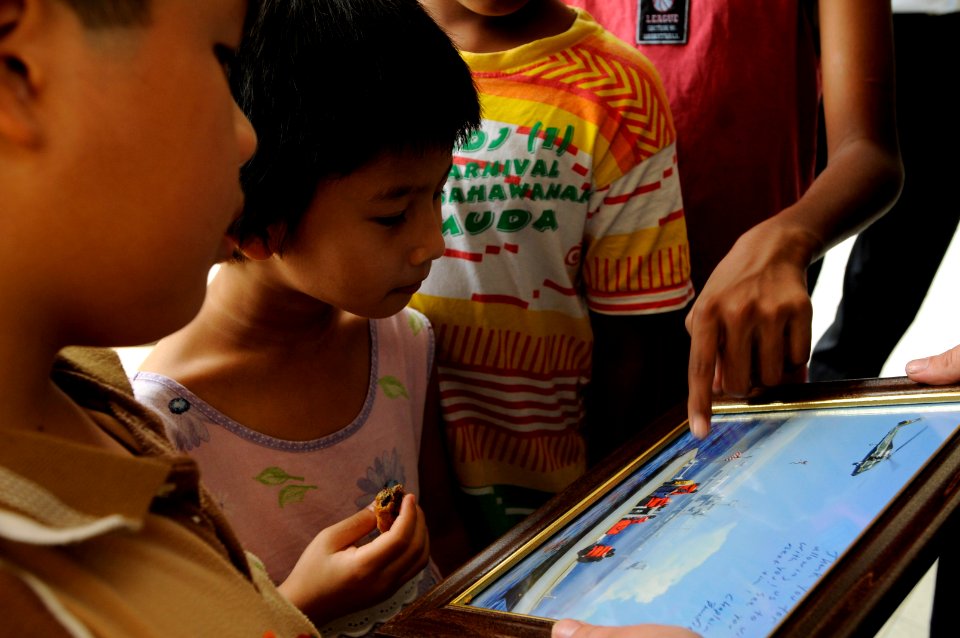 US Navy 091027-N-3830J-307 Children from the Praise Emmanuel Children's Home look at a picture presented to the home by Sailors assigned to the amphibious command ship USS Blue Ridge (LCC 19)