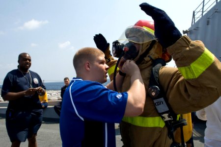 US Navy 091025-N-9123L-033 Chief Navy Career Counselor Tony Turner keeps time as Damage Controlman 2nd Class Dakota Bingham, from Parsons, Kan., helps Hull Technician 2nd Class Donipaul Briscoe, from West Plains, Mo., don a fir