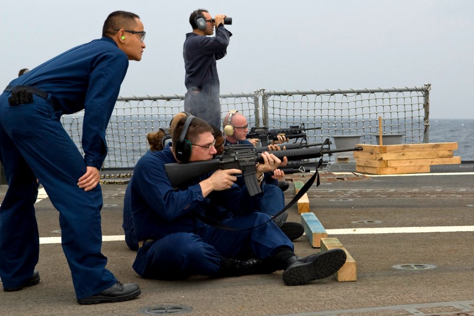 US Navy 091026-N-9123L-010 Fire Controlman 2nd Class Chaung Pha, from Sacramento, Calif., observes as Senior Chief Operations Specialist Travis Biswell, from Fayetteville, Ark., fires an M-16 rifle during small arms qualificati