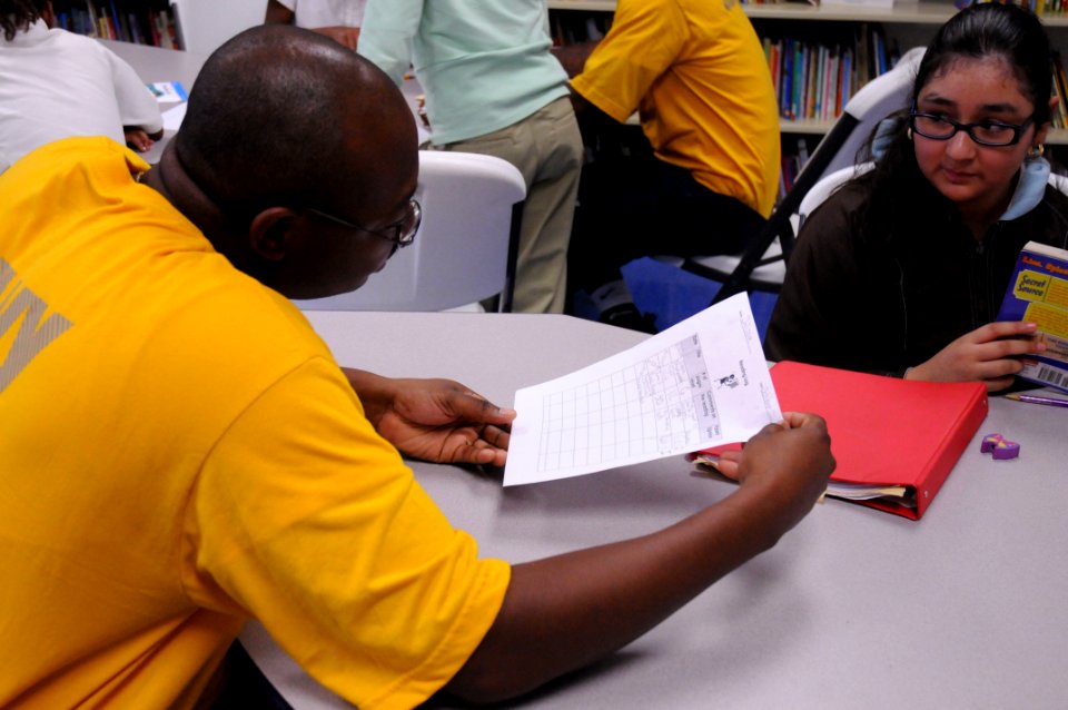US Navy 091029-N-6220J-016 Aviation Boatswain's Mate (Fuels) 1st Class Ulric Carter reviews a young girl's reading homework at the Finnigan Park Boys and Girls Club